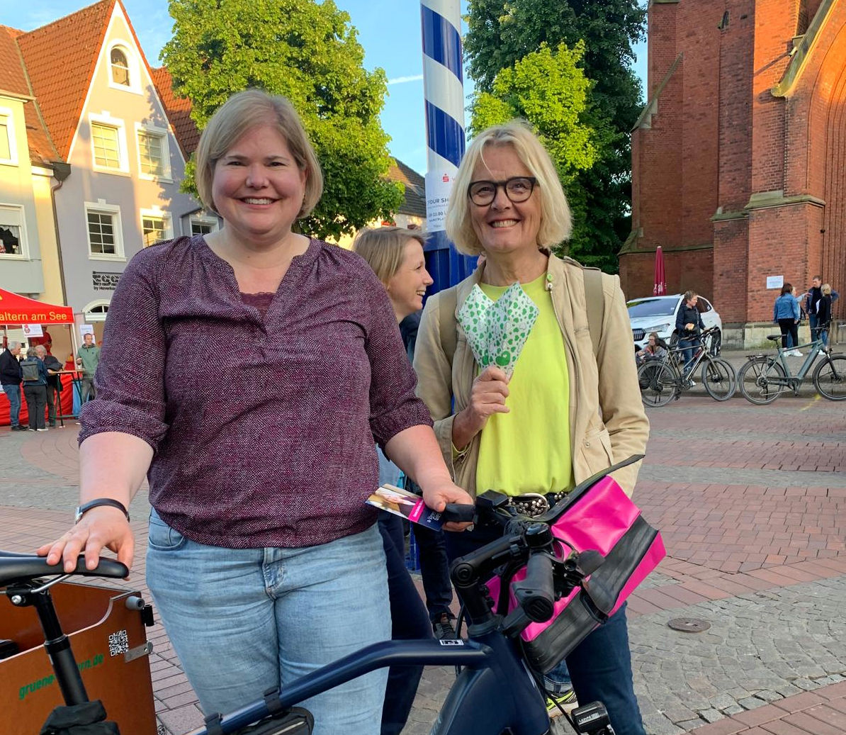 Vanessa und eine große, blonde Frau auf dem Marktplatz vor ienem Maibaum. Die Frau hält eine Popcorntüte in der Hand.