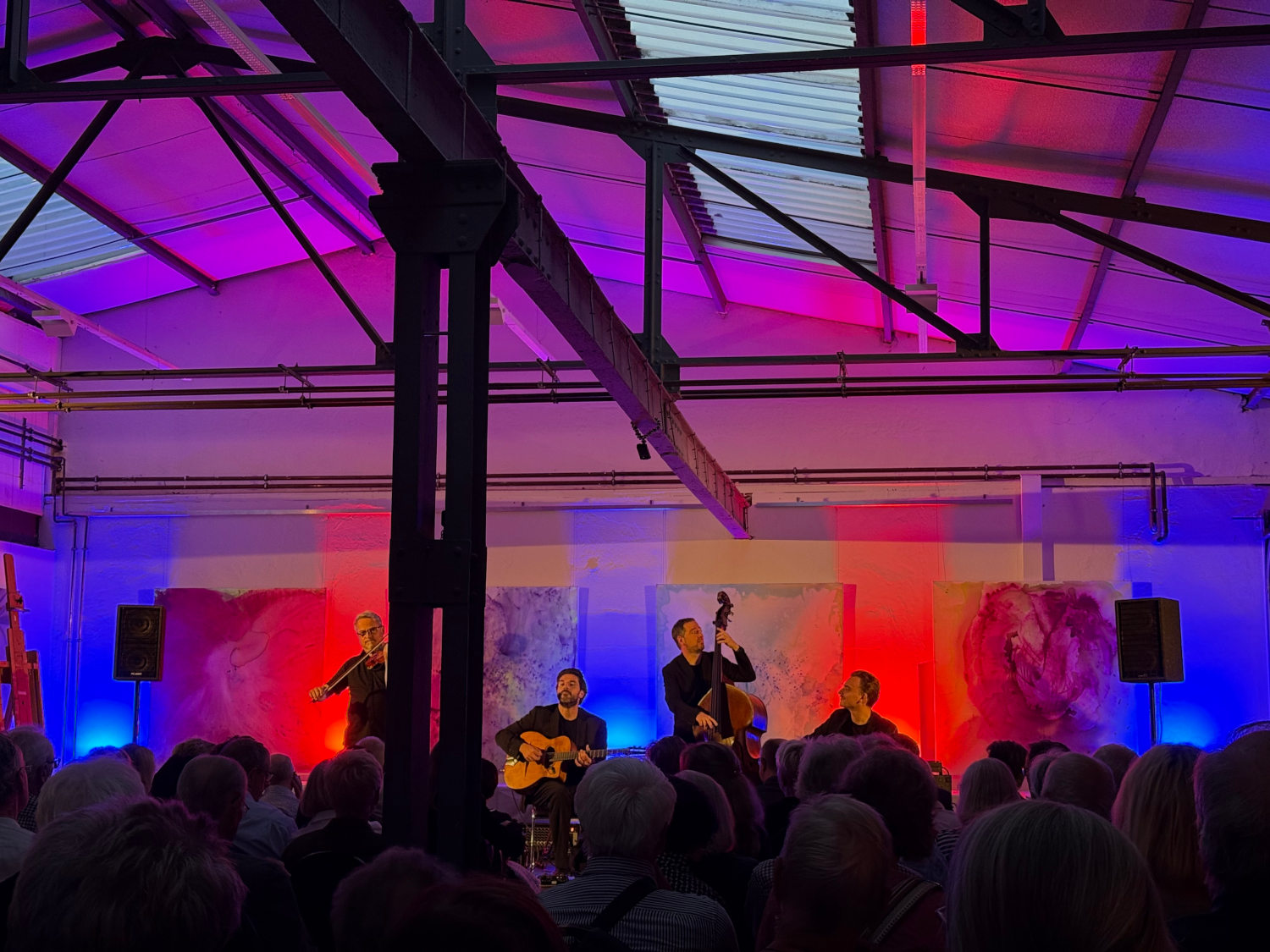 Vier Jazz-Musiker auf der Bühne, davor Publikum, bunte Beleuchtung.