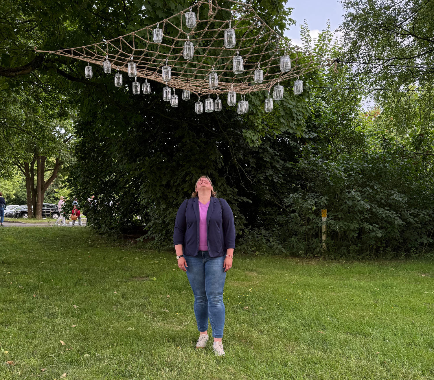Vanessa steht auf einer Wiese unter einem Netz mit Gläsern