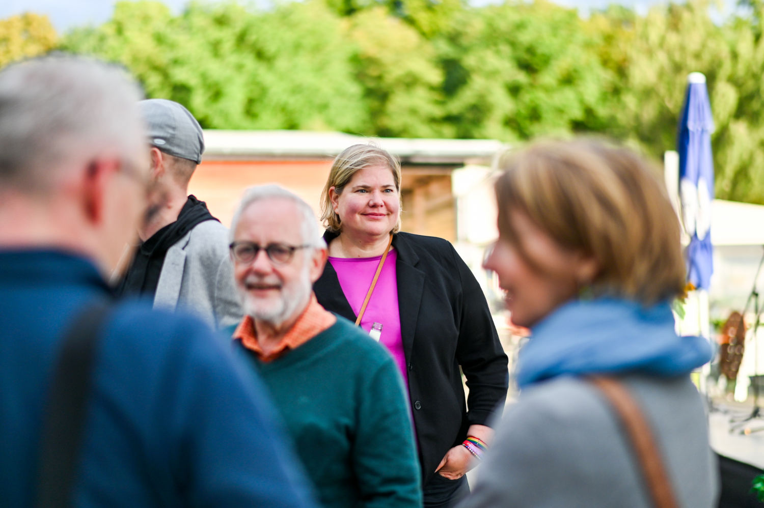 Vanessa zwischen älteren und ittelalten Menschen, sie schaut in die Ferne