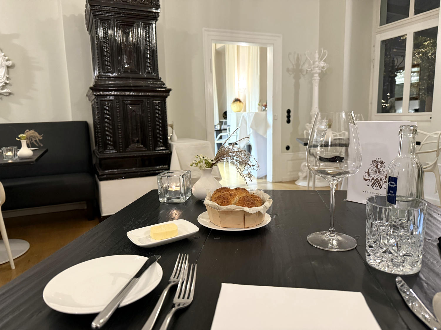 Schwarz-weißes Ambiente, ein fein gedeckter Tisch, darauf ein Korb mit Brot
