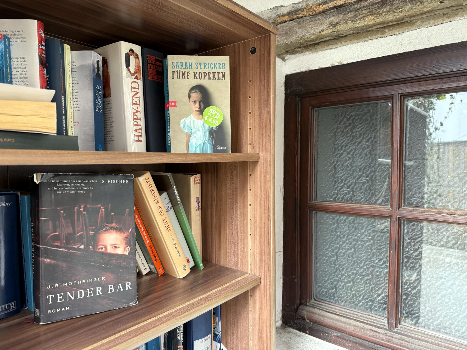 Bücherschrank, "Fünf Kopeken" sichtbar im Regal, darunter "Tender Bar".