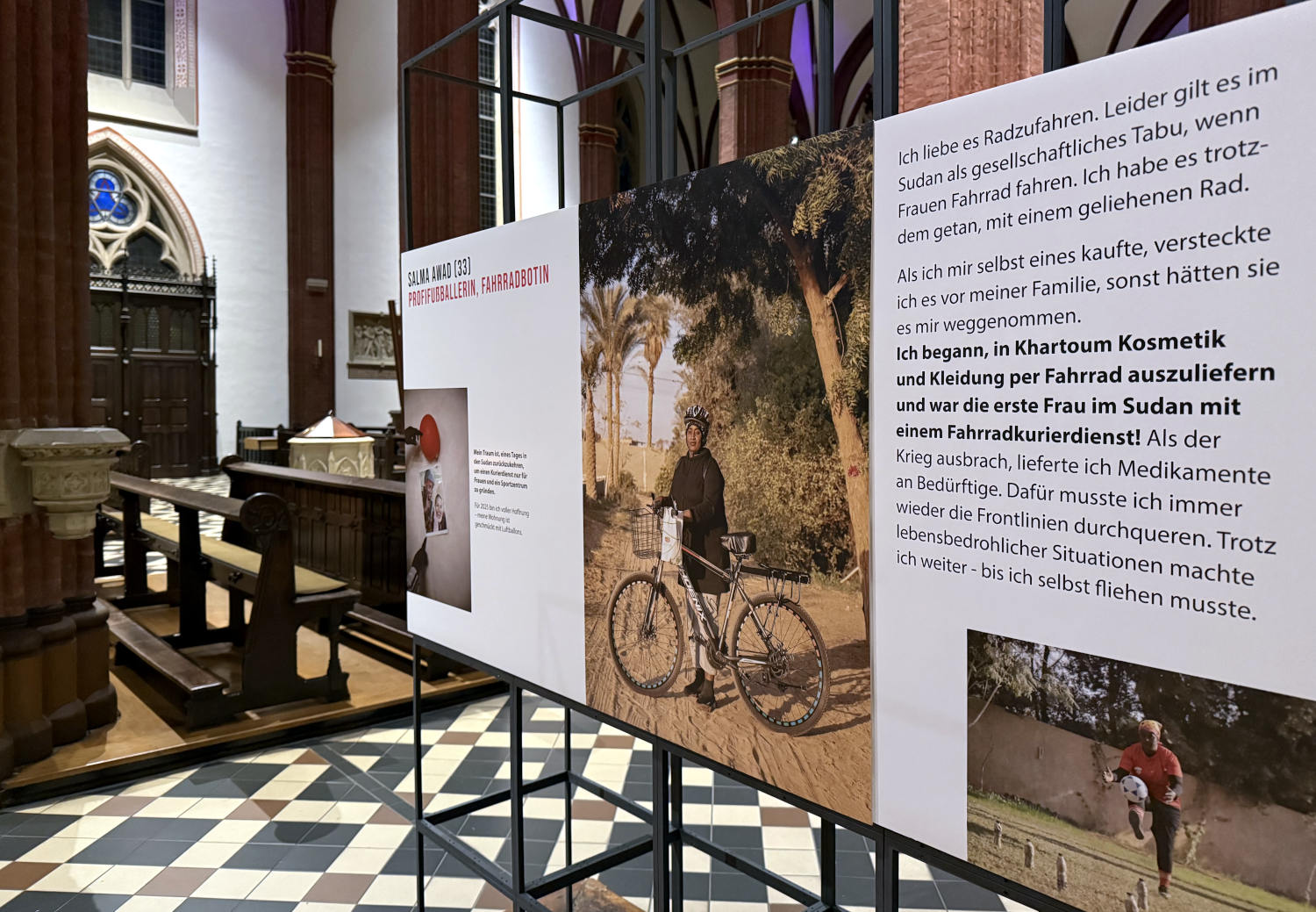 Fotos und Erzählung einer Fahrradbotin im Sudan, aufgestellt auf einer Tafel in einer Kirche