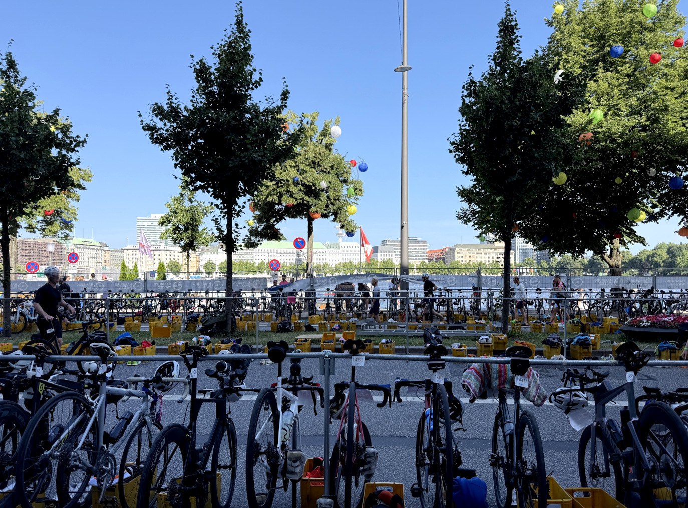 Ganz viele Fahrräder, aufgehängt an Metallstangen und mit Startnummern versehen, am Jungfernstieg. Läufer laufen ins Bild. Im Hintergrund Fahnen und Ballons.