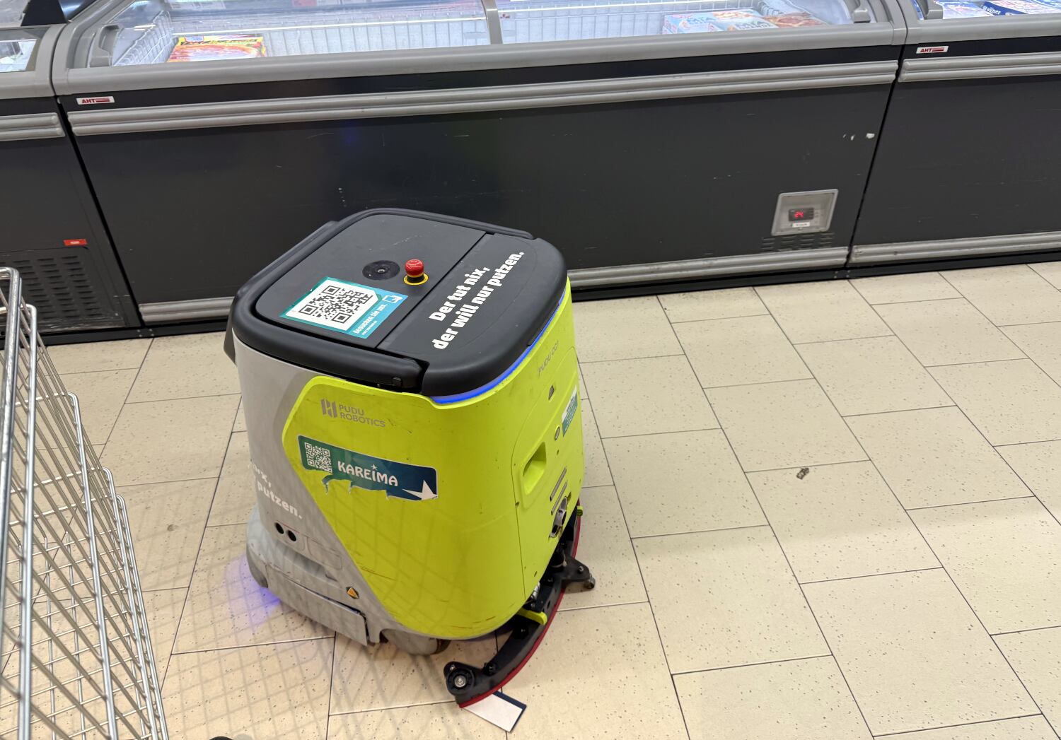 Putz-Roboter vor der Tiefkühltruhen. Auf ihm steht: Der tut nix. Der will nur putzen.